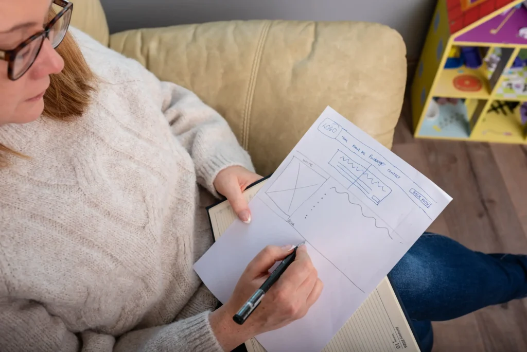Louise Cook, Galway web designer, sketching a website wireframe by hand while seated on a sofa