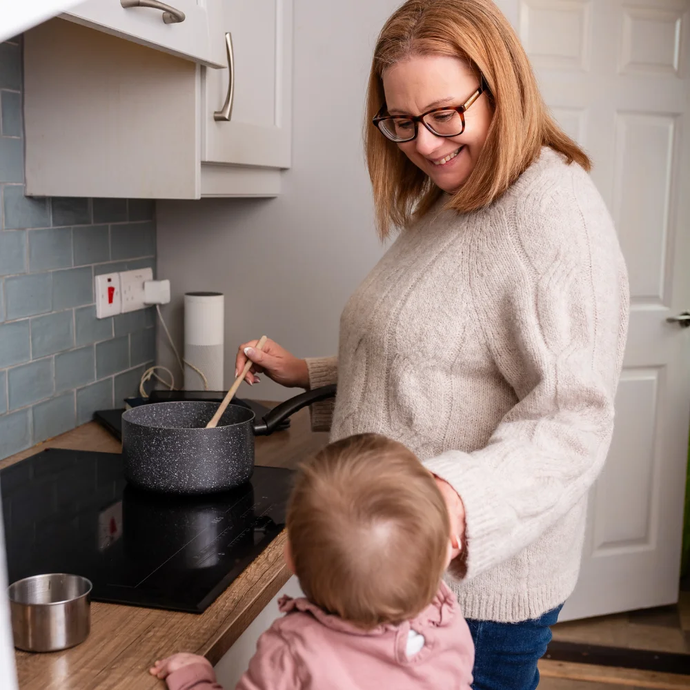 Louise Cook, Galway web designer and mother, cooking in the kitchen while her baby looks on
